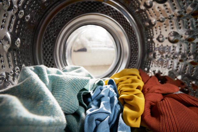Photo of the inside of a washing machine with clothes in it.